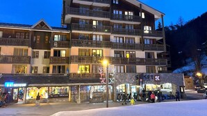 A multi-story hotel with balconies and a ski resort sign in the foreground.