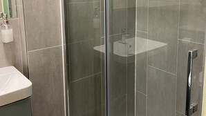 Un bagno moderno con doccia vetrata, lavandino bianco e specchio.