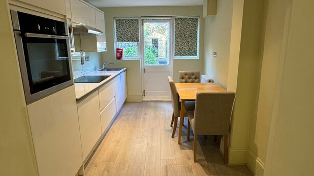 Una cucina moderna con elettrodomestici integrati, un'area pranzo con tavolo e sedie, e vista attraverso una finestra.