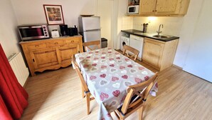 Une cuisine compacte dotée de meubles en bois, d’un four à micro-ondes, d’un réfrigérateur, d’un évier et d’une table à manger avec des chaises.