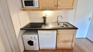 Une cuisine de taille réduite, dotée de meubles en bois, d’un four à micro-ondes, d’un lave-vaisselle et d’un évier.