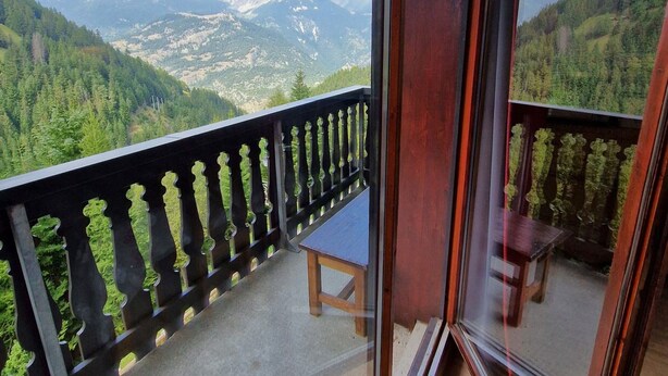 Un balcon avec vue sur les montagnes et la forêt.