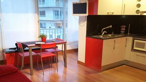 Cocina compacta con fregadero, estufa y un pequeño comedor con mesa y sillas.