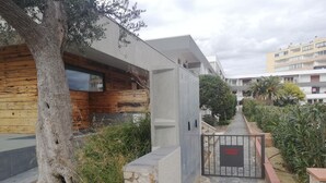 Propiedad privada con sendero de piedra, estructuras de madera y hormigón, y entrada con portón.