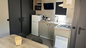 Cocina compacta con refrigerador, microondas, cafetera y estufa a gas.