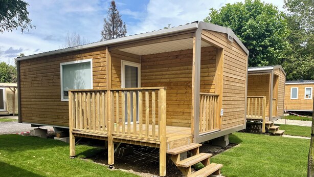 Una casa móvil de madera con porche, ventana y puerta.