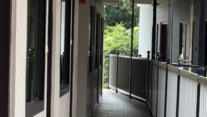 A corridor with patterned flooring, a metal railing, and a view of greenery outside. - Periyar Holidays  (Peermade)