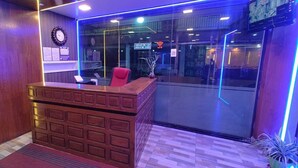 A reception desk with a red chair, wooden paneling, and a clock on the wall. - Periyar Holidays  (Peermade)