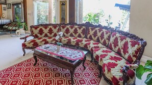 A living room with a patterned sofa, a glass-top coffee table, and a red and white patterned rug. - Collection O Puncak Bogor Near Taman Safari Indonesia Formerly Hotel Andalus (Megamendung)