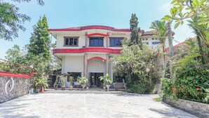 A two-story building with a red roof and columns, surrounded by greenery and potted plants. - Collection O Puncak Bogor Near Taman Safari Indonesia Formerly Hotel Andalus (Megamendung)