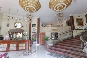 Un amplio vestíbulo con mostrador de recepción, una escalera y un techo decorativo.