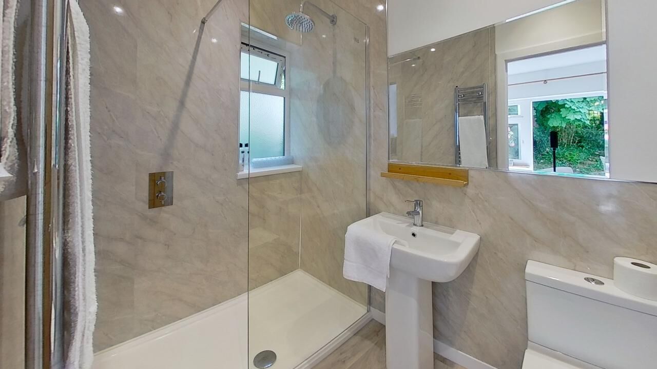 Une salle de bain moderne avec une douche à parois de verre, un lavabo blanc et un grand miroir.