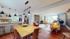 Amplia sala de estar con una mesa de comedor de madera, varias sillas, un sofá y un piano.