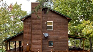 A wooden cabin with a porch, a chimney, and a satellite dish. - Escape to Serenity: Cozy Mountain Cabin with Mountain View/Pet Friendly (Sevierville)