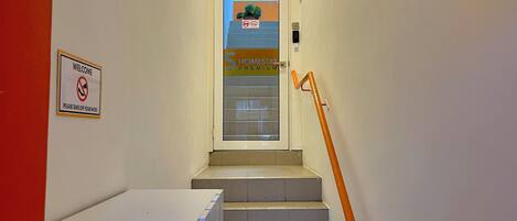 A hotel entrance with a 'Welcome' sign and a 'Please take off your shoes' sign.