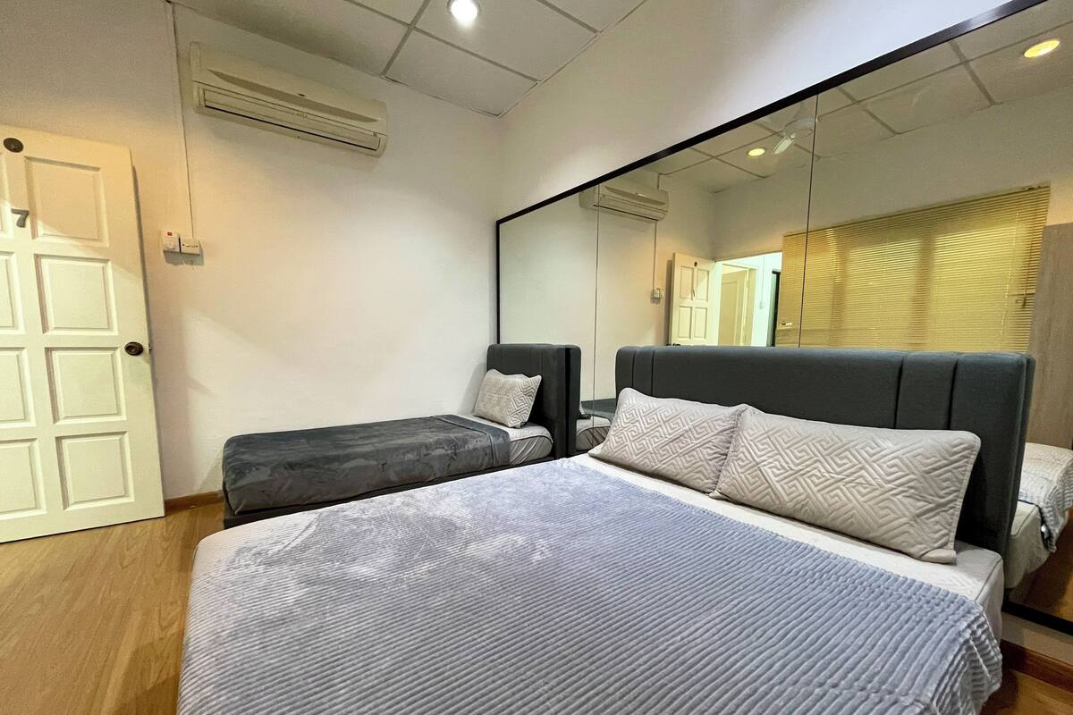 A bedroom with a large bed, a smaller bed, a mirror, and an air conditioning unit.