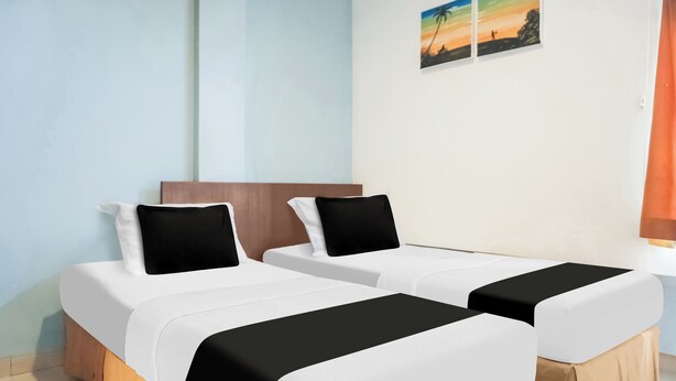 A hotel room with two beds, each with white bedding and black headboards. - Collection O Bukit Kecil Near Palembang Indah Mall  Formerly Hostel 77 (Palembang)