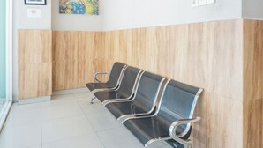 A waiting area with three black metal chairs and a wooden wall. - Collection O Bukit Kecil Near Palembang Indah Mall  Formerly Hostel 77 (Palembang)