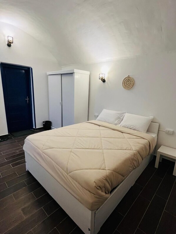 A bedroom with a bed, a wardrobe, a door, and a wall-mounted light fixture. - Sharqotel Luxor (Luxor)
