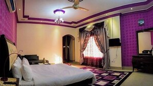Une chambre à coucher avec un lit, une commode, un miroir et un ventilateur de plafond.