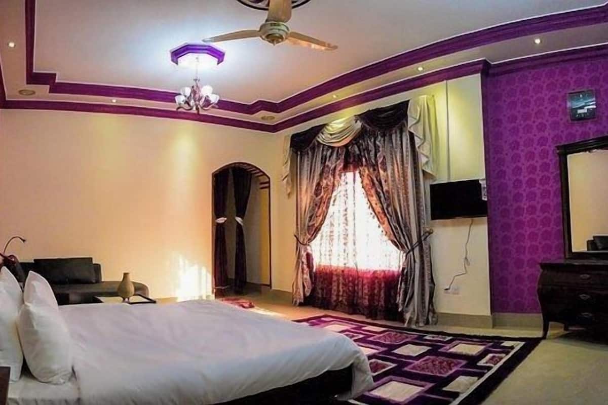 A bedroom with a bed, a dresser, a mirror, and a ceiling fan.