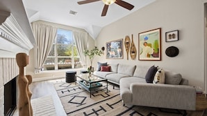 A living room with a sofa, coffee table, and artwork on the wall. - Eclipse · Artist Retreat @ Cypress Creek | Hotub | Sleeps 9 (Cedar Park)