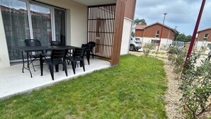 Propiedad residencial con patio amoblado, mesa y sillas, puerta corrediza de vidrio y cerco de madera.