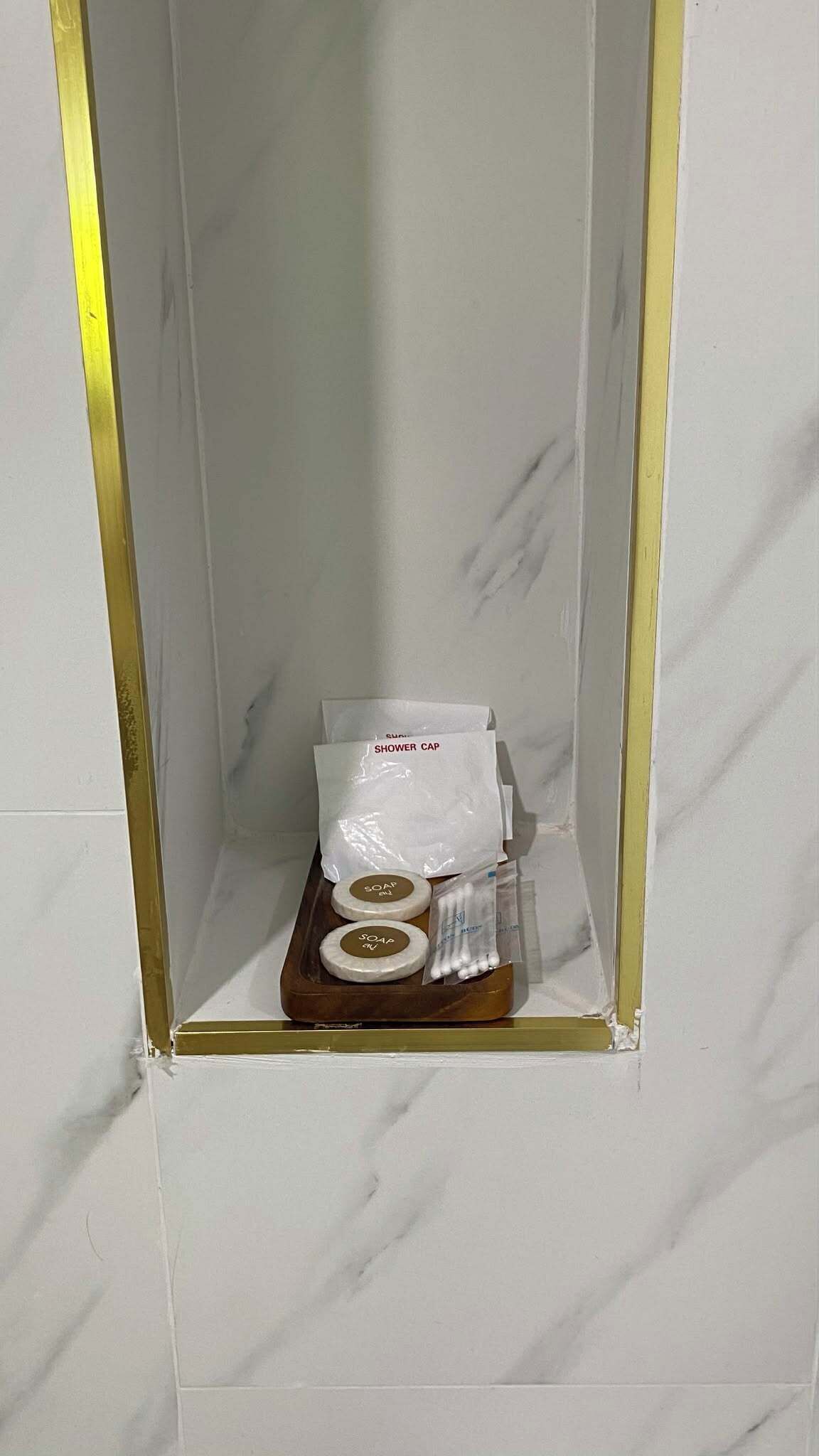 Une salle de bain comprenant un espace douche, un porte-savon, un bonnet de douche et un savon.