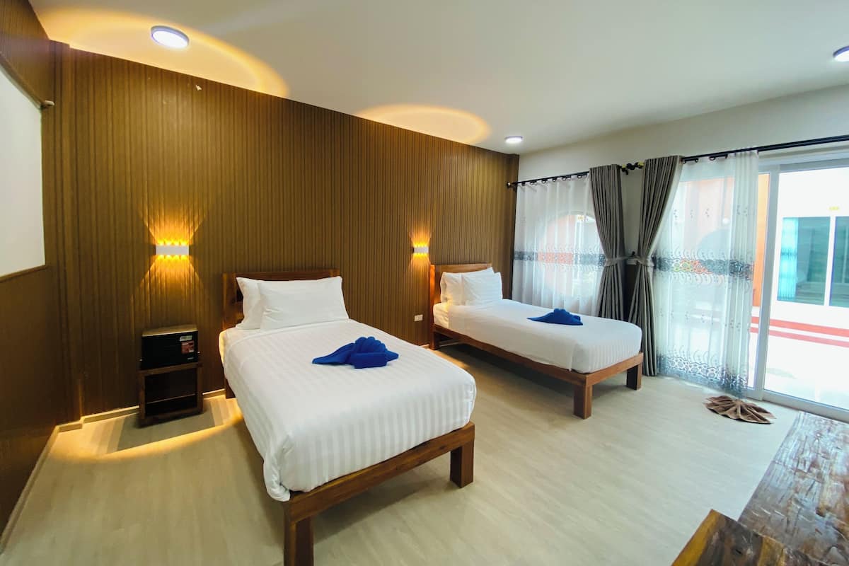 A hotel room with two beds, wooden headboards, and a large window with curtains.