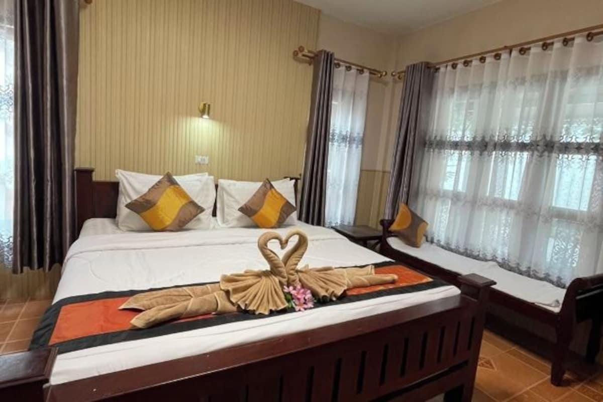 Une chambre d’hôtel avec un lit, des rideaux et une disposition décorative des serviettes.