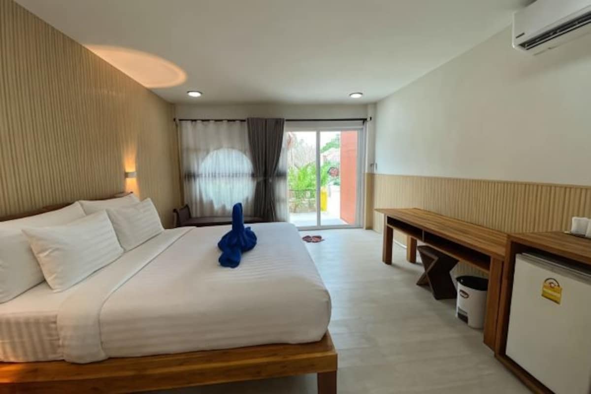 Une chambre d’hôtel équipée d’un lit, d’un bureau, d’une chaise, d’une poubelle et offrant une vue sur l’extérieur.