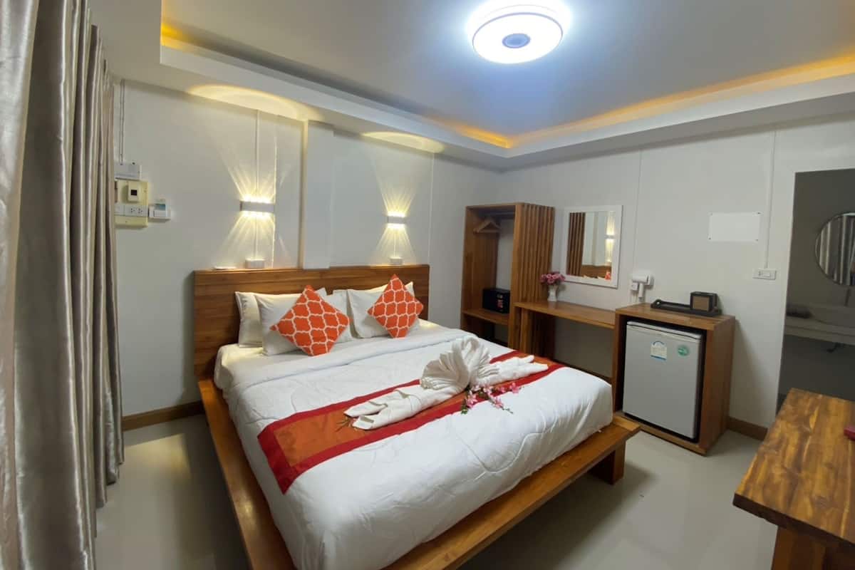 A hotel room with a bed, bedside table, mirror, and a small desk with a chair.