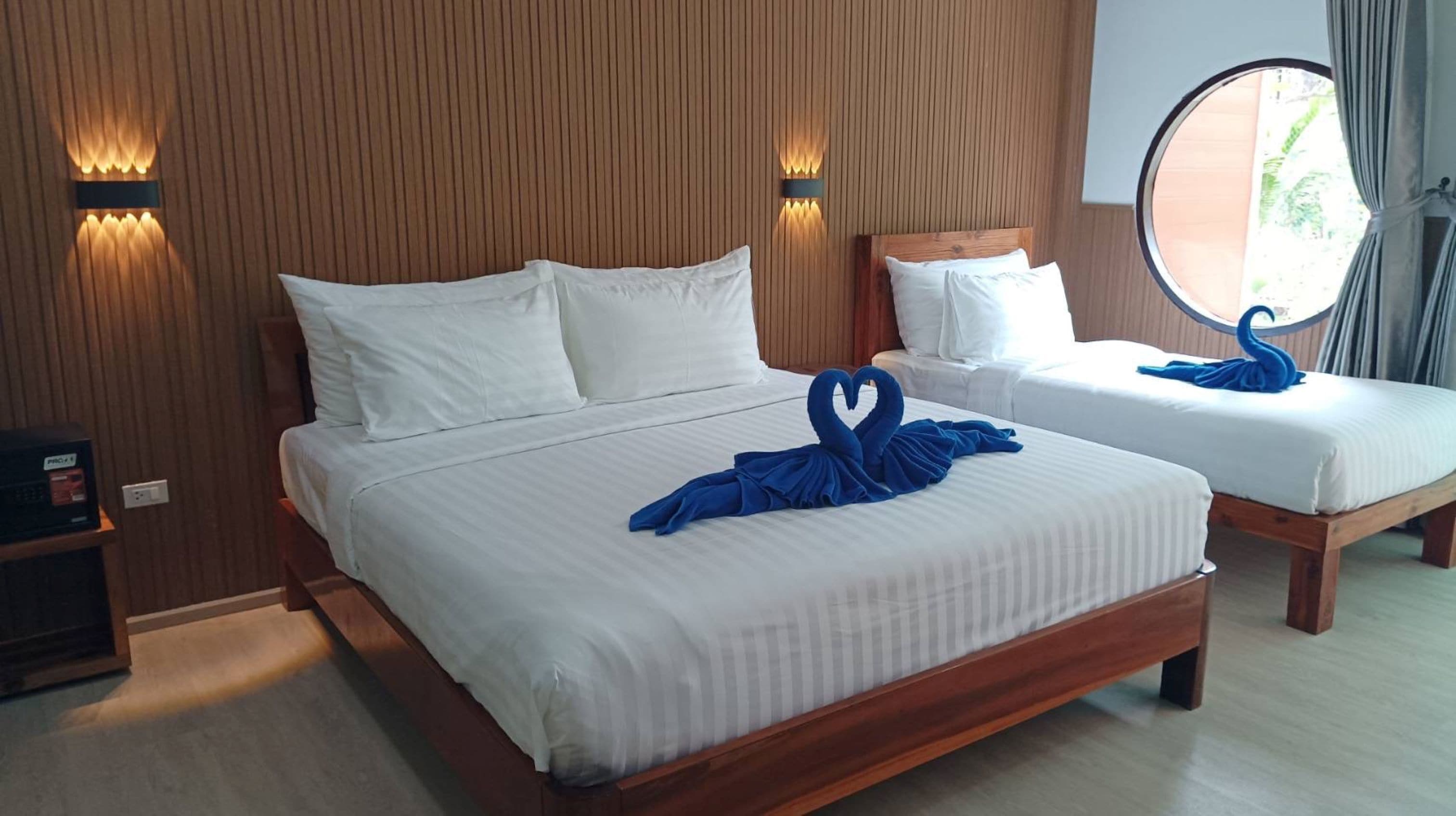 A hotel room with two beds, each with white linens and pillows. There are wall-mounted light fixtures on either side of the beds.