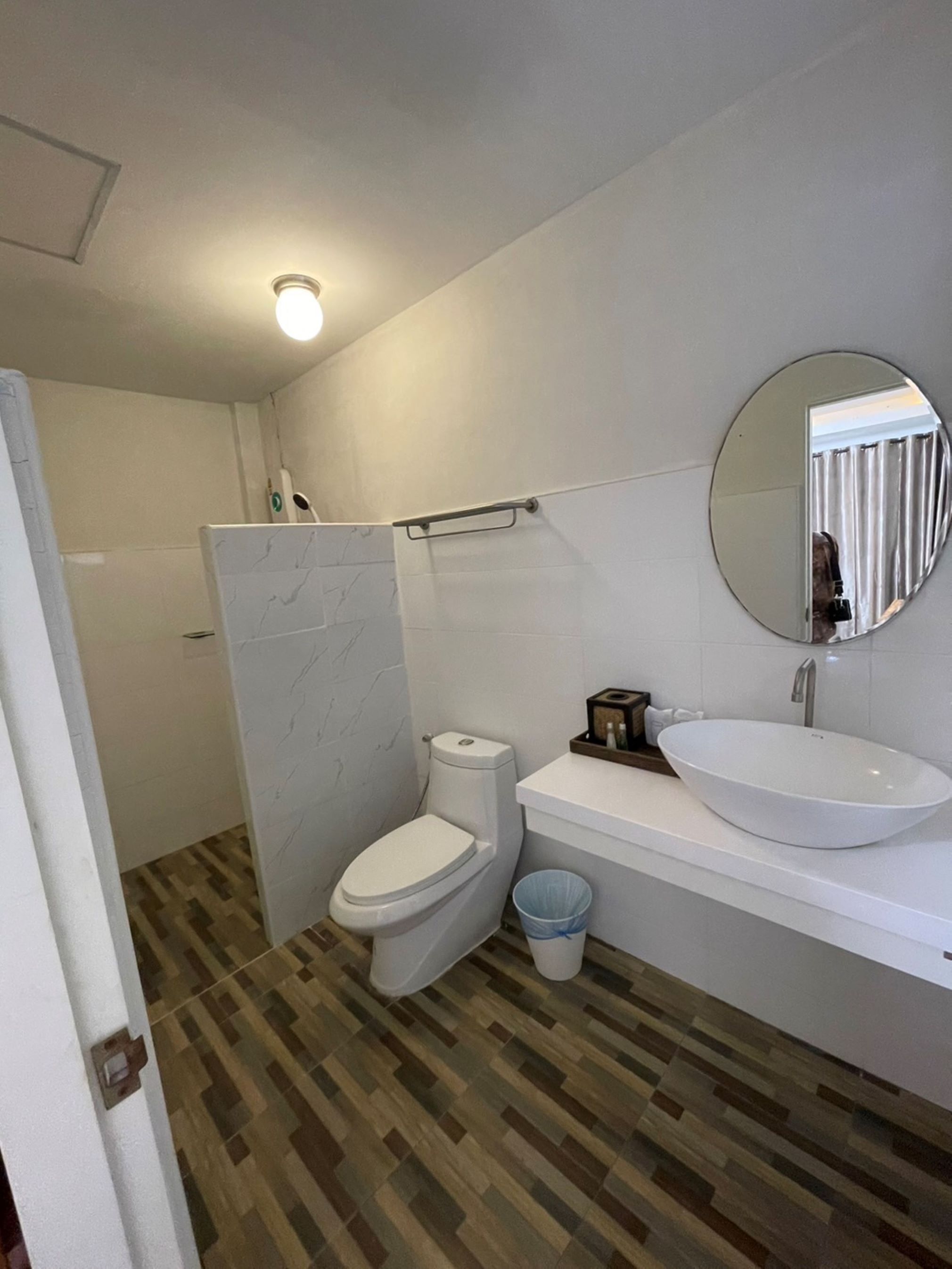Et badeværelse med toilet, vask og spejl.