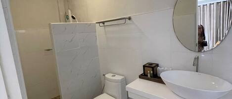 Et badeværelse med toilet, vask og spejl.