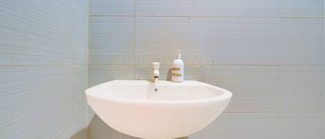 A bathroom with a white sink, a faucet, and a soap dispenser.
