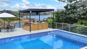 A rooftop pool with a wooden deck, seating area, and a view of the surrounding landscape. - Hotel Mirador Cielo Blue-20Min Guatapé. (El Peñol)
