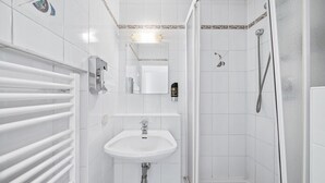 A bathroom with a white sink, a mirror, a towel rack, and a shower area.