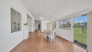 A corridor with a dining area, white walls, and a view through a gate. - Reef Shack Beach Vibes Stroll to the beach (Kurrimine Beach)