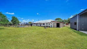 A residential property with a large lawn, a house with a garage, and a swimming pool. - Reef Shack Beach Vibes Stroll to the beach (Kurrimine Beach)