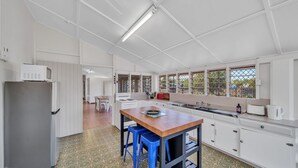 Una cocina moderna con armarios blancos, una isla de madera, taburetes de bar azules y vistas por la ventana.