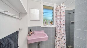 Un baño con un lavabo rosa, una ventana con vistas y una cortina de ducha con estampado color melocotón.