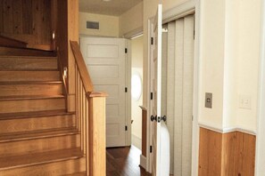 A wooden staircase leading to a white door with a vent above it.