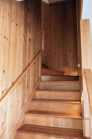 Una escalera de madera con barandilla que lleva a un piso superior.
