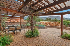 A covered patio with brick flooring, outdoor furniture, and a view of mountains. - BunnyLand Lodge | Panoramic Mt. Views | Fantastic Backyard Patio | Scenic Location in Flagstaff (Flagstaff)