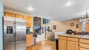 A modern kitchen with stainless steel appliances, wooden cabinets, and a stone accent wall. - ACE - A Hole in One! | Right on the Golf Course | Hot Tub |  Mt Views & Pines (Flagstaff)