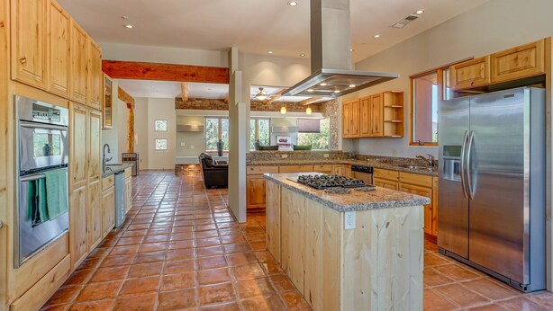 Una cocina amplia con armarios de madera, una isla central y electrodomésticos de acero inoxidable.