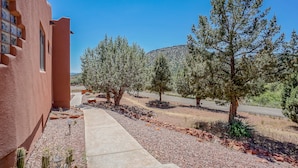 Un edificio de fachada roja, un camino de hormigón y una variedad de árboles y cactus en el paisaje circundante.