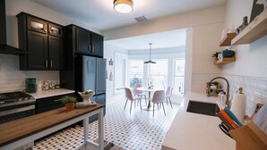 A modern kitchen with dark cabinets, a wooden countertop, and a patterned floor. - Doc's Place | Historic Jewel In Downtown Flagstaff | Sophisticated Elegance (Flagstaff)