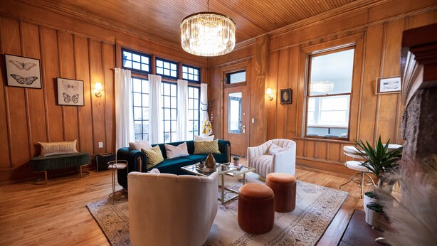 A cozy room with wooden paneling, a chandelier, a sofa, a chair, and a coffee table. - Doc's Place | Historic Jewel In Downtown Flagstaff | Sophisticated Elegance (Flagstaff)